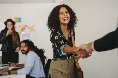 Young woman shakes shakes hands with someone out of frame