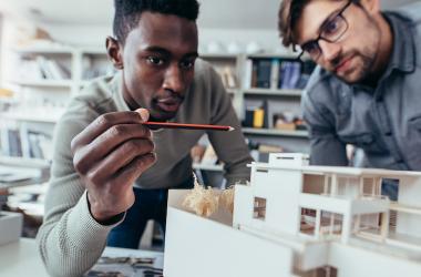 Two young men examine a model of a house